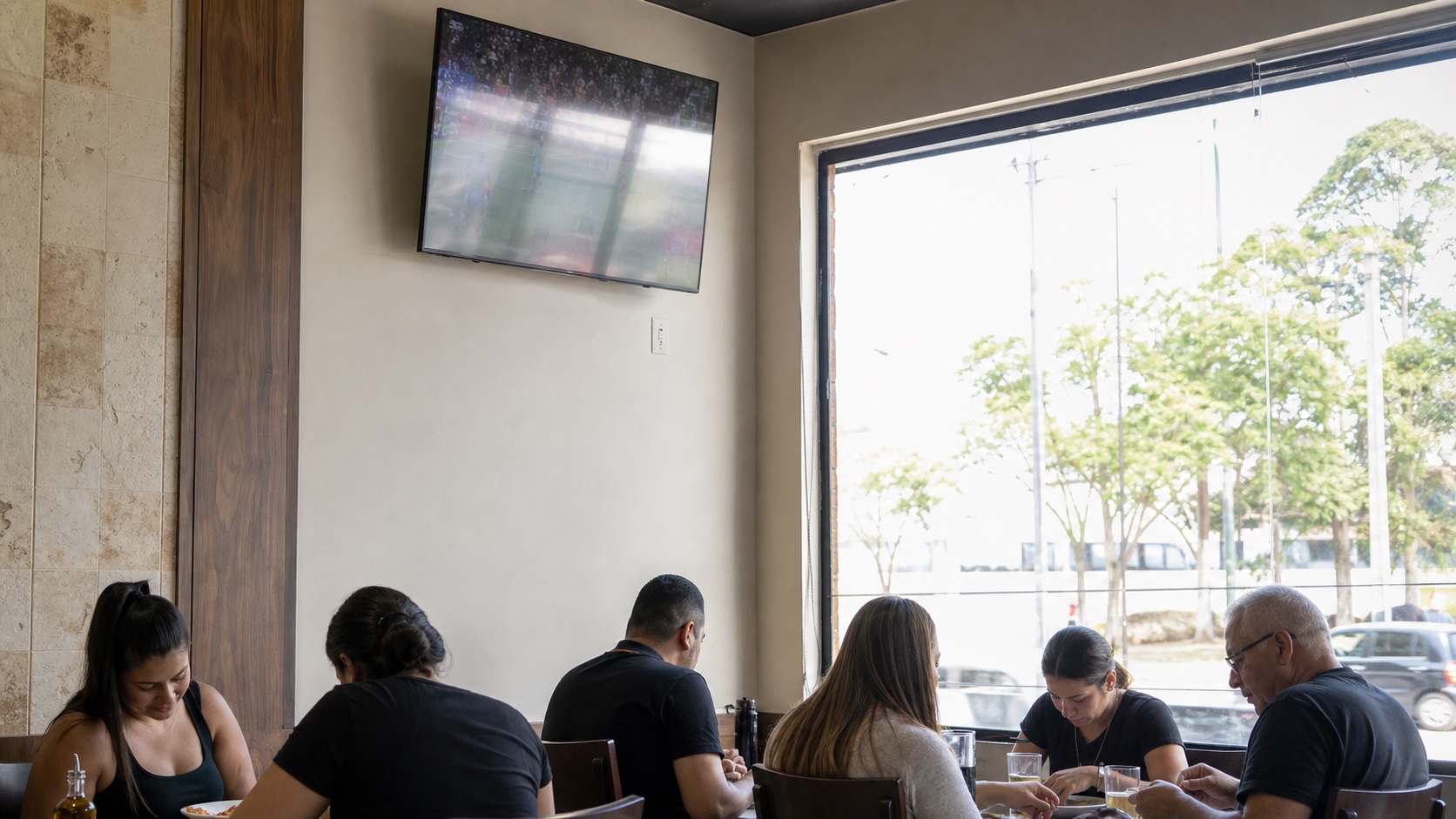 TV instalada alta demais em um restaurante, com reflexo da janela lavando a imagem, enquanto os clientes olham para a mesa